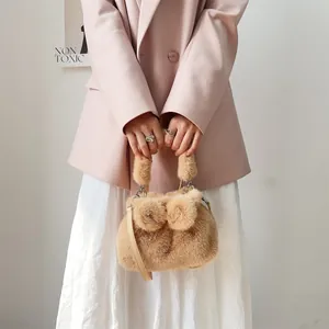 Nahaufnahme einer weichen Handtasche aus Nerzimitat mit eleganter Schleife in Camel