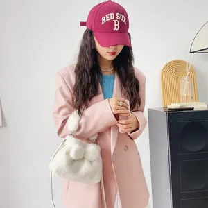 Detail der weißen Plüsch-Handtasche aus Nerzimitat mit Schleife, kombiniert mit rosa Blazer