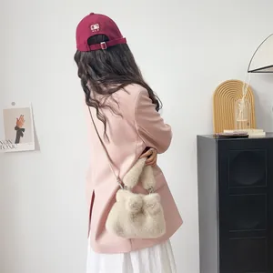 Nahaufnahme der cremefarbenen Kunstpelztasche mit Schleife über einem rosa Blazer.