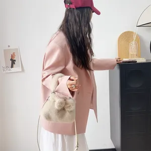 Seitenansicht einer weichen beigen Kunstpelltasche, kombiniert mit einem rosa Blazer.