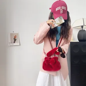 Detailansicht einer roten Plüsch-Handtasche mit Schleife, getragen zu einem rosa Blazer