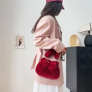 Detailansicht einer weichen roten Plüschtasche mit Schleife, getragen zu einem rosa Blazer