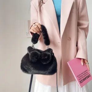 Detailansicht einer stylischen schwarzen Kunstfelltasche mit süßen Schleifen-Pompons