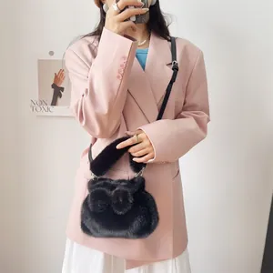 Modische schwarze Kunstpelz-Schleifen-Handtasche in einem Lifestyle-Foto mit rosa Blazer