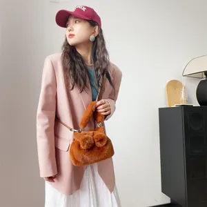 Detailaufnahme einer braunen Kunstpelz-Handtasche mit Schleifenakzenten an einem Model.