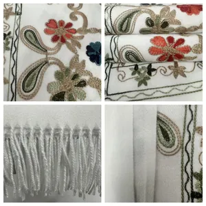Close-up details showing premium floral embroidery and fringe tassels on a white shawl