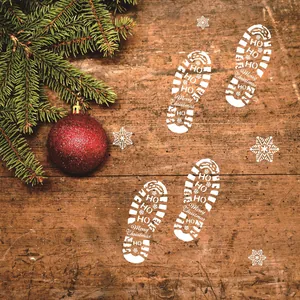 Detailed view of white Christmas footprint stencil designs with festive text on rustic wood surface.