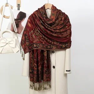 Vue détaillée d'une écharpe en jacquard rouge drapée sur un manteau blanc élégant