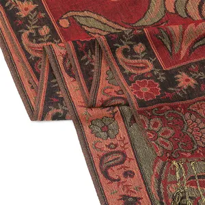 Gros plan du motif paisley floral en jacquard rouge et or sur un châle pashmina