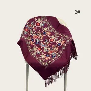 High-quality close-up of intricate floral embroidery and tassels on a maroon pashmina