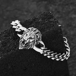 Detailaufnahme eines maskulinen silbernen Löwenkopf-Anhängers an einem groben Panzerarmband.