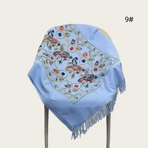 Macro view of the intricate floral paisley embroidery on this elegant light blue fringed shawl.