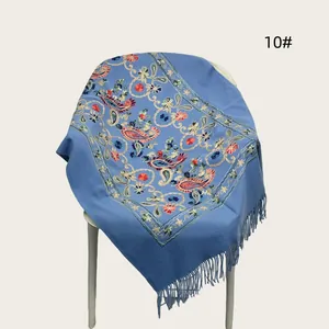 Detailed view of blue embroidered floral scarf featuring elegant fringe and tassel design