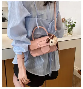 Vue détaillée d'un sac à main rose en cuir huilé avec breloque ours sur modèle