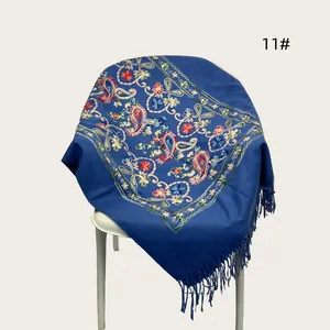 Detailed macro view of a blue embroidered floral scarf with elegant tassel trim