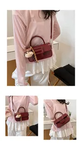 Vues détaillées du sac bandoulière en cuir ciré rouge avec une breloque d'ours peluche.
