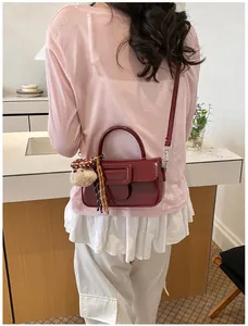 Vue arrière d'un sac bandoulière chic en cuir verni bordeaux avec un charmant chien