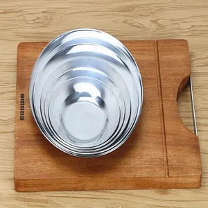 Detail of four nested 410 stainless steel round plates on a rustic wooden board surface