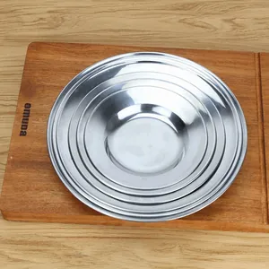 Set of five round stainless steel plates stacked neatly on a wooden board for display