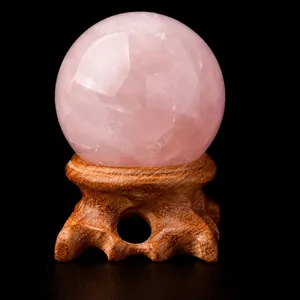 Large natural pink rose quartz crystal sphere with ornate wooden stand for home meditation decor