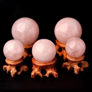Detailed view of five natural rose quartz crystal spheres on ornate wood bases