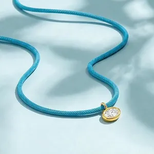 Primer plano de collar bohemio de cordón azul claro con colgante de circón chapado en oro.