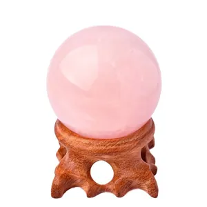 Natural rose quartz crystal sphere resting on a carved wooden base for elegant home decor