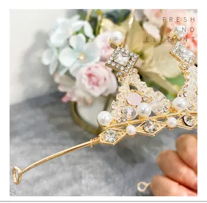 Close-up of gold-plated children's princess crown with elegant pearls and rhinestones.