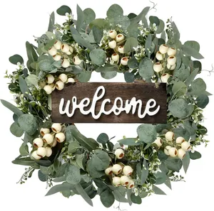 Close-up of a rustic artificial eucalyptus wreath with white berries and a welcome wood sign