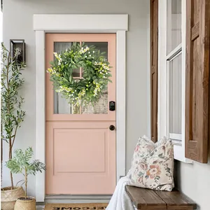 Artificial eucalyptus leaf and berry wreath decorating a modern pink front door in a cozy porch.