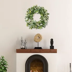 Artificial eucalyptus and white berry wreath hanging above a fireplace mantel