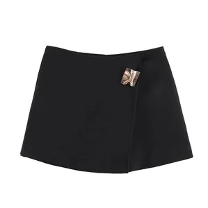 Detail view of the black skort's asymmetrical wrap front and chic gold buckle.