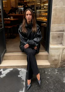 Street style view of oversized black faux leather jacket for women in cafe setting