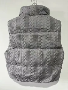 Close-up back view of a grey cable knit puffer vest showing detailed winter texture.