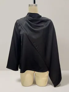 Detalle de una elegante blusa de satén negro con un diseño de chal drapeado asimétrico