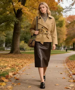 Elegante gabardina corta beige con cinturón y solapas en un bello parque de otoño.