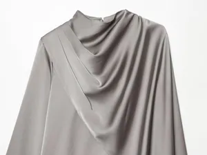 Primer plano de una elegante blusa de satén gris con cuello drapeado y diseño plisado.