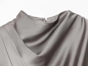 Detalle de top de satén plateado con escote de chal drapeado y textura de tela suave.