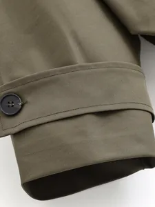 Close-up of olive green windbreaker cuff showing button and twill fabric detail