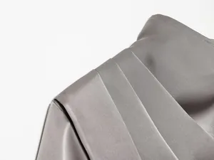 Primer plano del detalle del hombro plisado en un top de satén gris para mujer