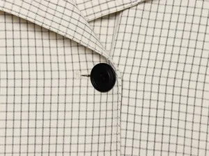 Makrodetail einer minimalistischen karierten Jacke mit schwarzem Knopf und Webstruktur