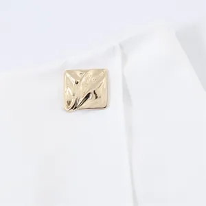 Detailed macro shot of a textured gold square button on a white asymmetric fashion skort