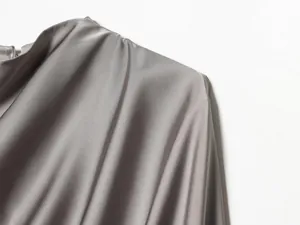 Detalle de blusa de satén gris plateado con elegante diseño de chal drapeado
