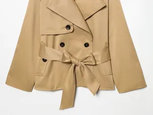 Detalle de una gabardina corta color caqui con cinturón y botones de doble botonadura