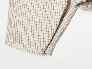 Nahaufnahme der Karo-Stoffstruktur und des Knopfdetails einer Jacke