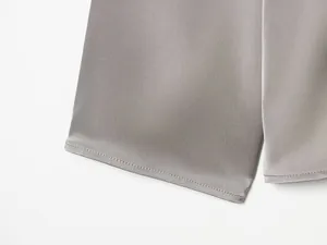 Primer plano de las costuras finas y el suave tejido de satén de esta blusa gris.