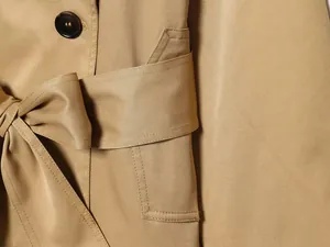 Primer plano de gabardina corta color kaki que muestra la textura y el cinturón