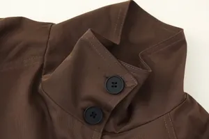 Macro view of the collar and matte black buttons on a stylish brown short trench coat.