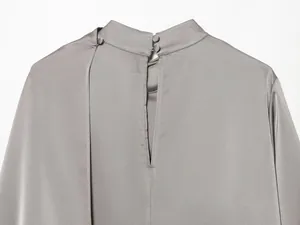 Detalle de blusa de satén gris con cuello alto y cierres de botones forrados en tela