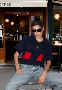 Close-up view of a stylish retro navy blue short sleeve knit sweater with red pockets.